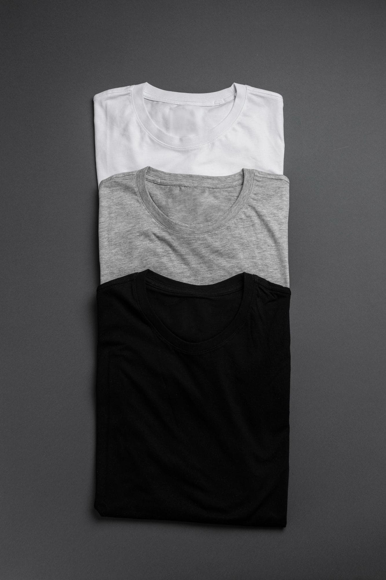 Folded white, grey, and black tees